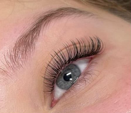 Wispy lash extensions on a blue-grey eye